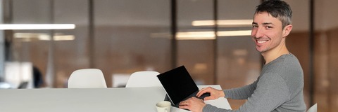 Personne assise dans un bureau, tenant un iPad ouvert et souriante